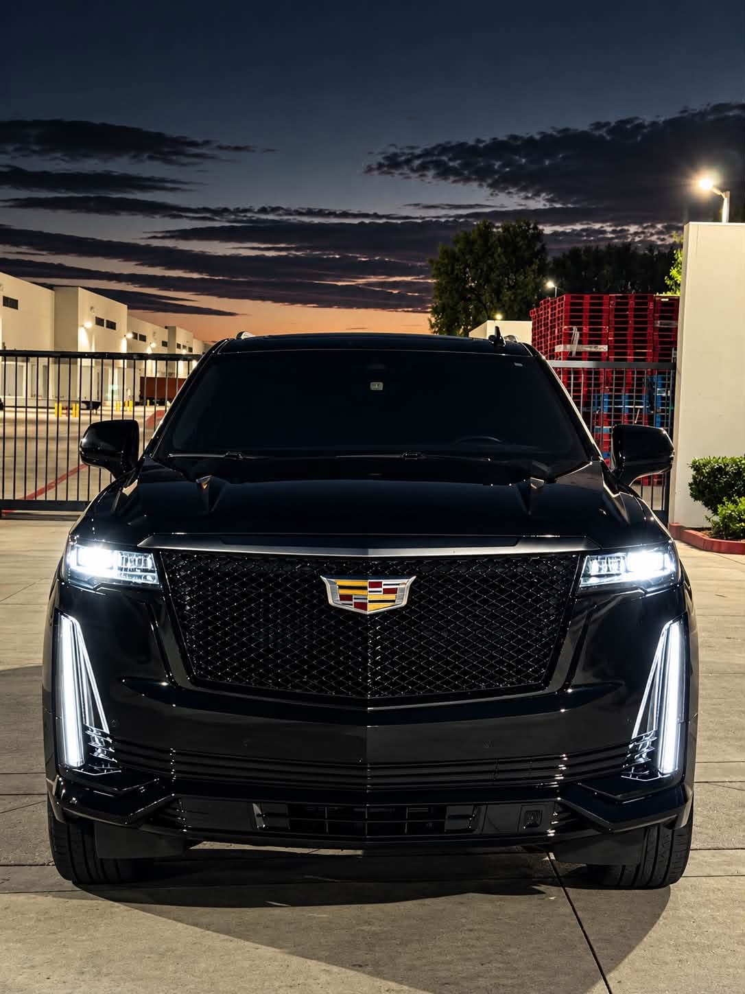 Black Cadillac at night, front view with headlights illuminated